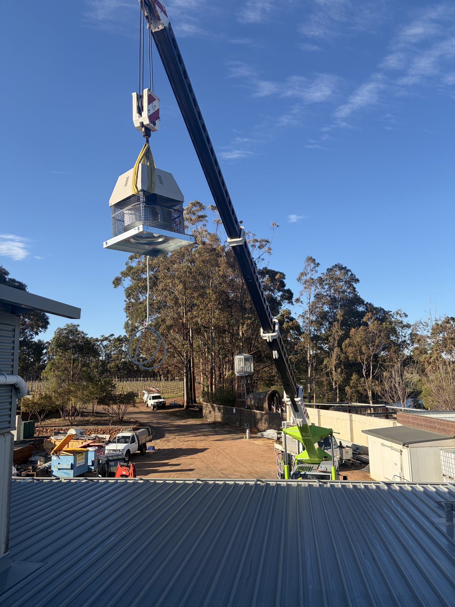 Westside Rigging 20 tonne Franna crane lifting an AC unit over the roofline, Wilyabrup